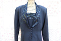 A black blazer with lace and sequin detailing on the lapel, displayed on a mannequin against a floral backdrop.