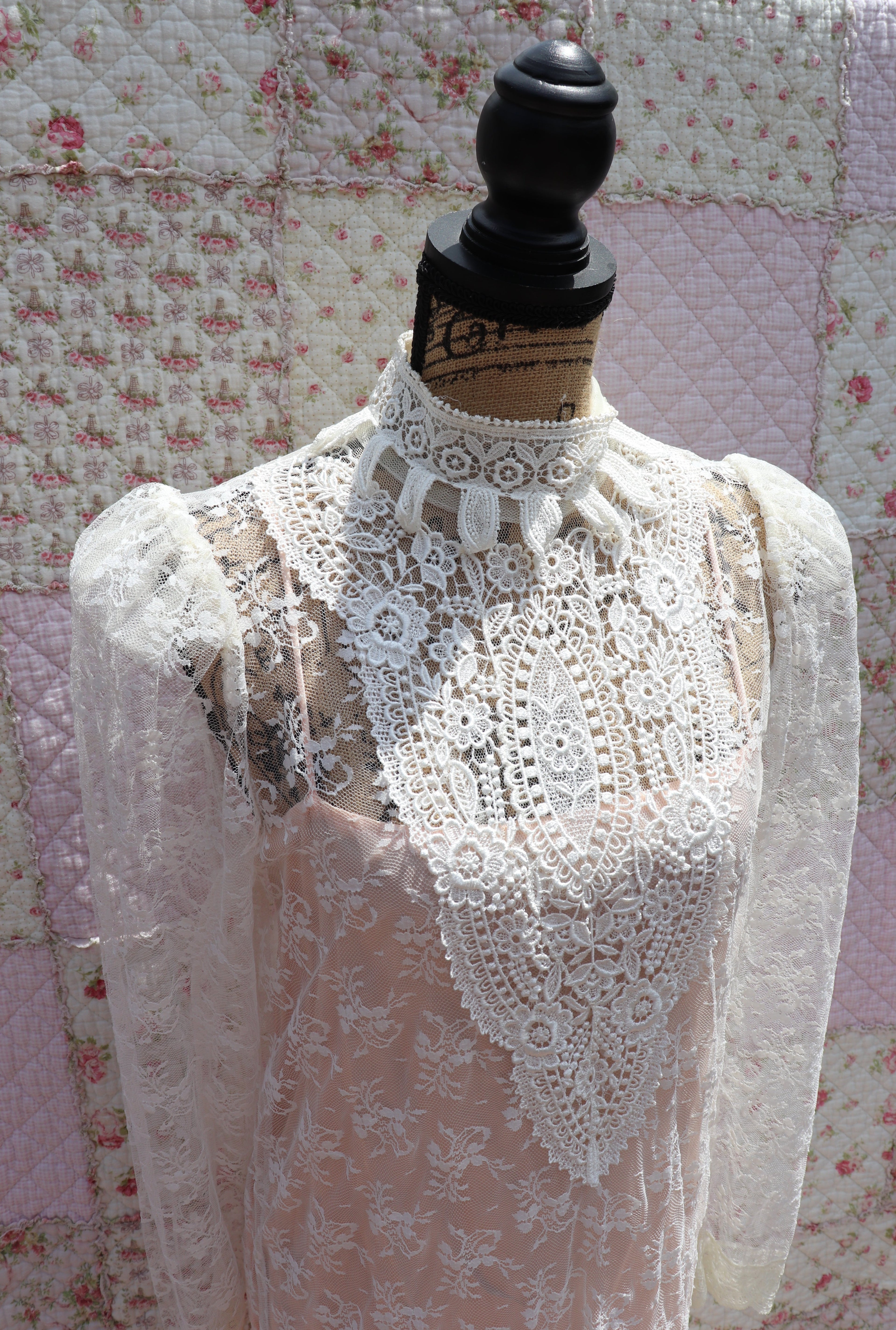 Get the best of both worlds with The Samantha Dress - a mashup of 1920s glamour and 1980s flair from Jessica McClintock. This white drop-waist puff shoulder turtleneck lace dress is laid over a delicate peach silk slip. Two for the price of one! Upgrade your wardrobe with this unique, versatile piece.