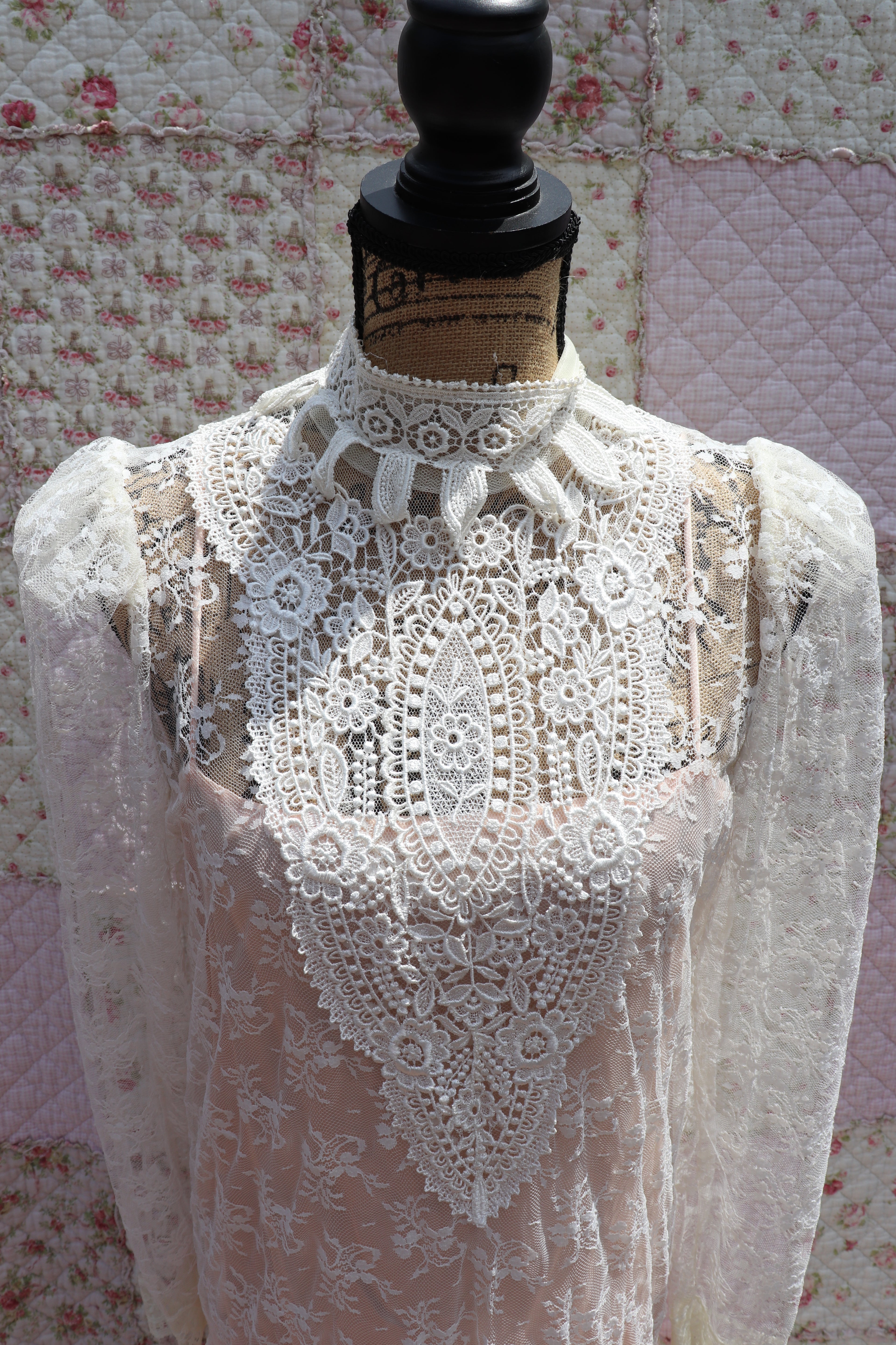 Get the best of both worlds with The Samantha Dress - a mashup of 1920s glamour and 1980s flair from Jessica McClintock. This white drop-waist puff shoulder turtleneck lace dress is laid over a delicate peach silk slip. Two for the price of one! Upgrade your wardrobe with this unique, versatile piece.