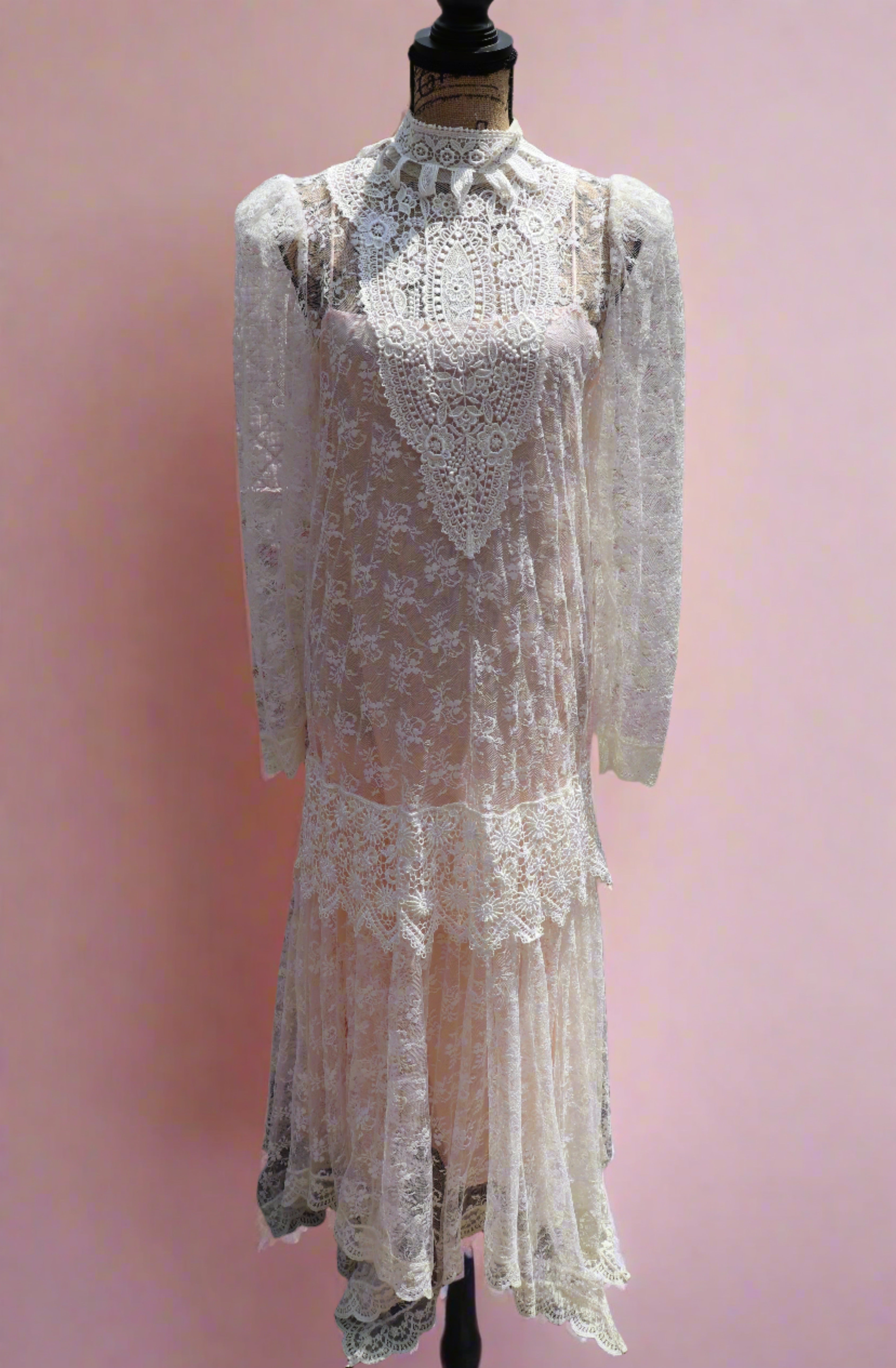 Get the best of both worlds with The Samantha Dress - a mashup of 1920s glamour and 1980s flair from Jessica McClintock. This white drop-waist puff shoulder turtleneck lace dress is laid over a delicate peach silk slip. Two for the price of one! Upgrade your wardrobe with this unique, versatile piece.