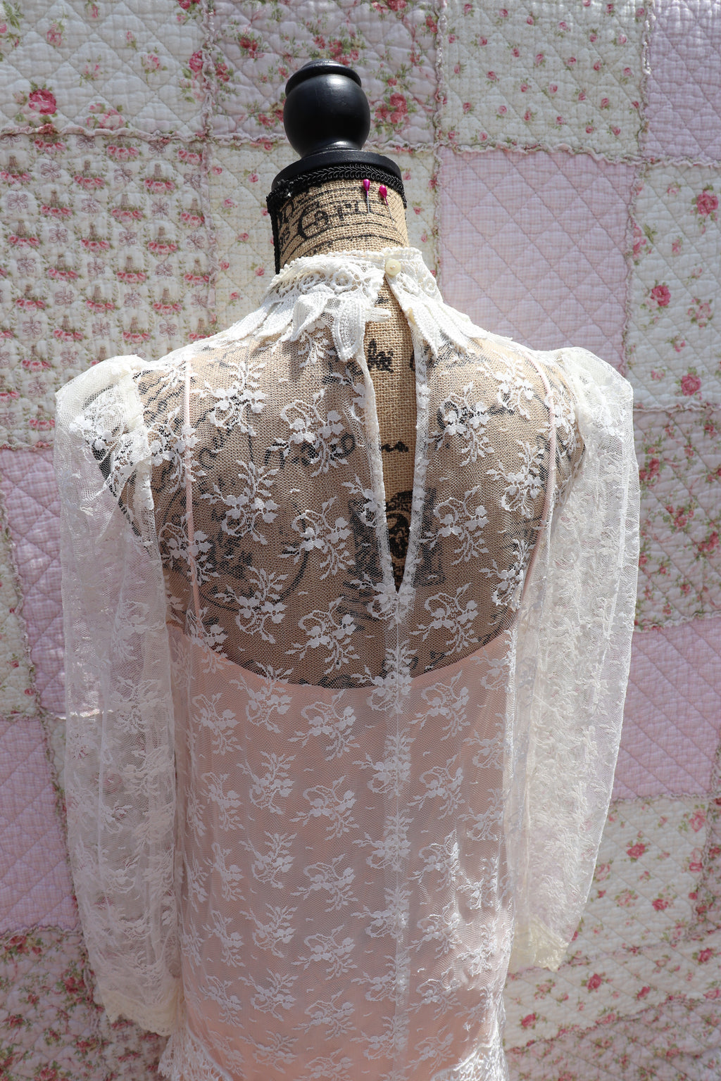 Back view of The Samantha Dress - a mashup of 1920s glamour and 1980s flair from Jessica McClintock. This white drop-waist puff shoulder turtleneck lace dress is laid over a delicate peach silk slip. Two for the price of one! Upgrade your wardrobe with this unique, versatile piece.