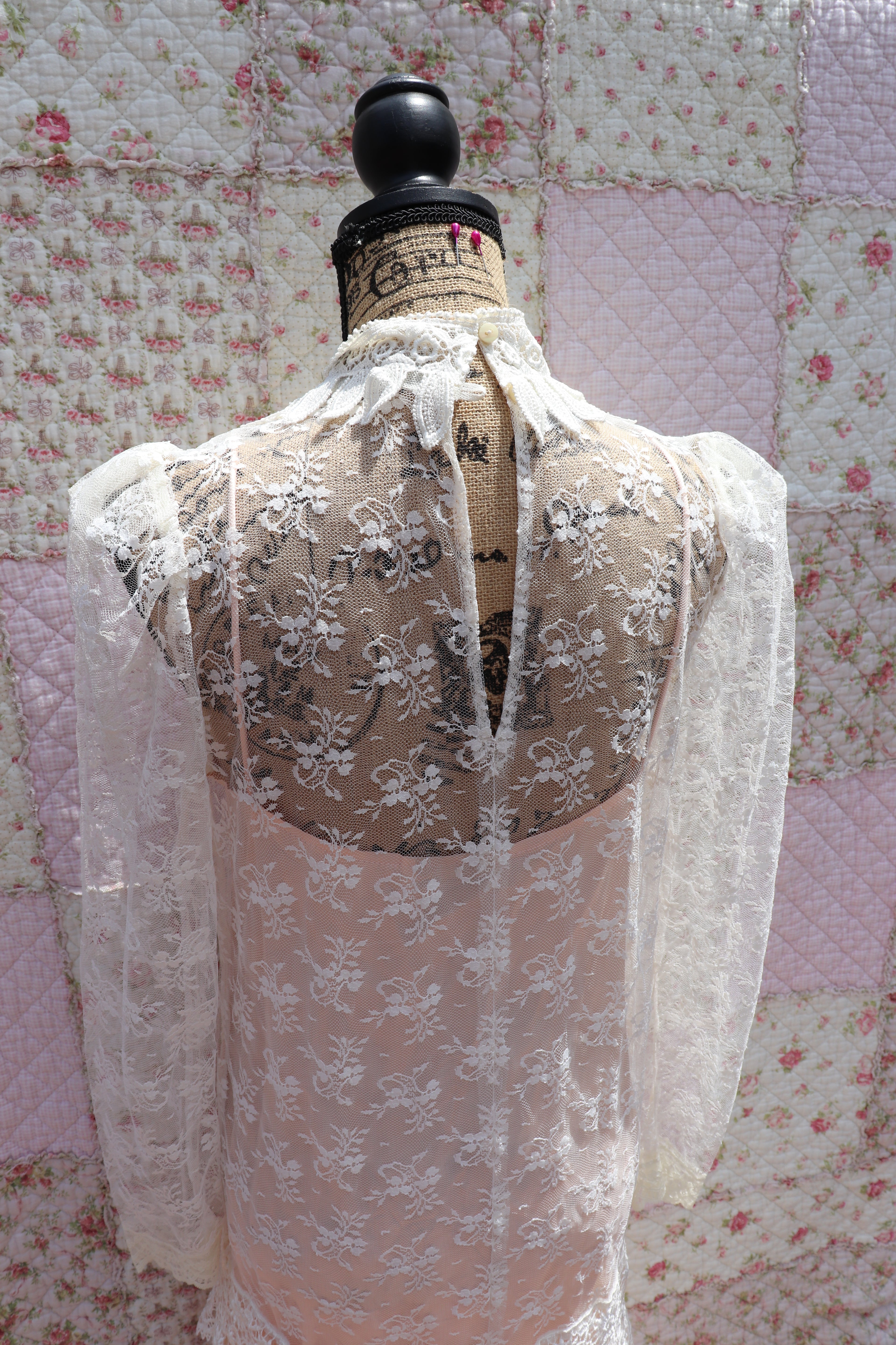 Back view of The Samantha Dress - a mashup of 1920s glamour and 1980s flair from Jessica McClintock. This white drop-waist puff shoulder turtleneck lace dress is laid over a delicate peach silk slip. Two for the price of one! Upgrade your wardrobe with this unique, versatile piece.