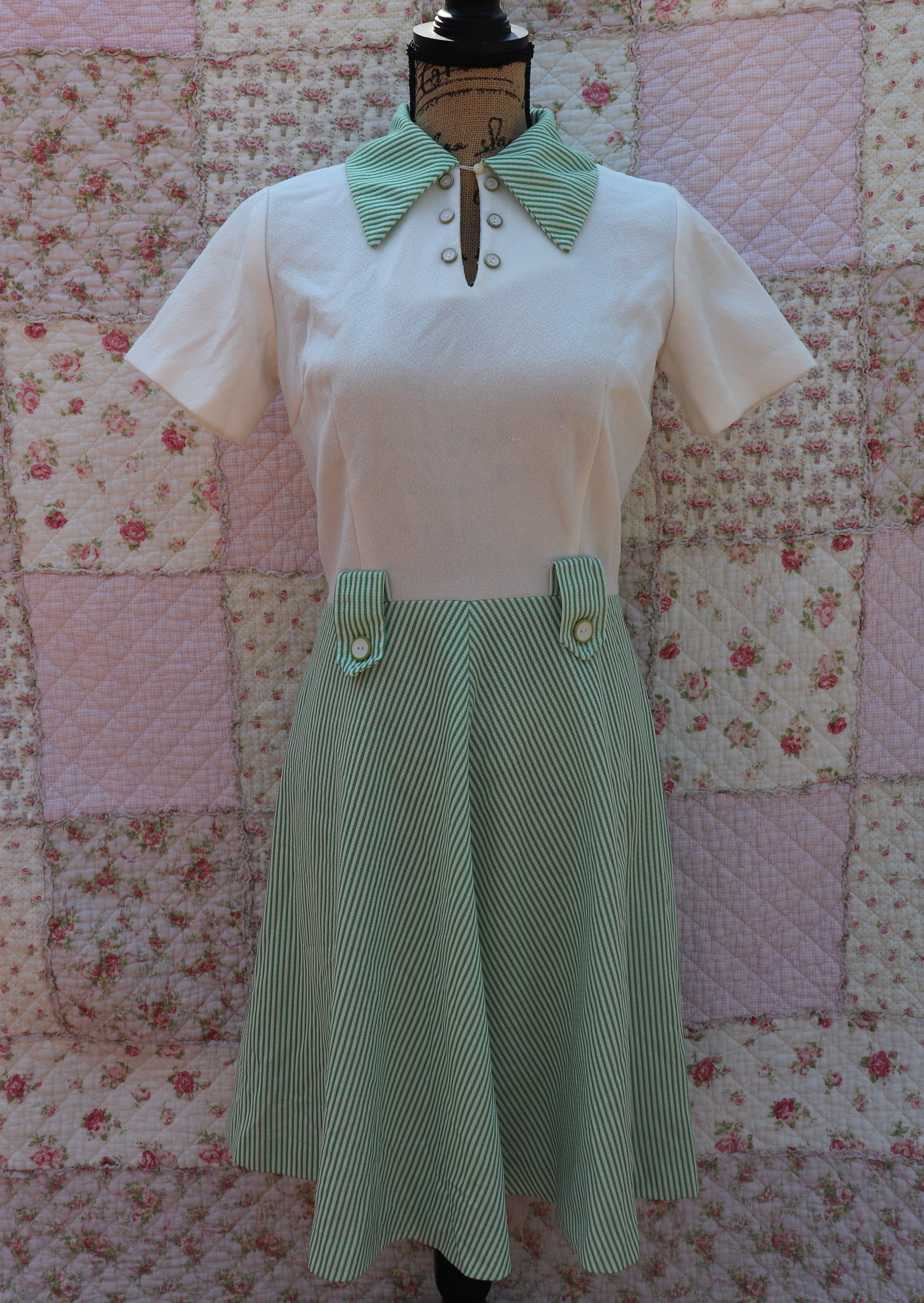 Full view of the Mabel Dress: a playful 1970s throwback. This white terry cloth dress features a green pinstripe skirt and collar, with a small cutout and cream buttons on the neck for added cuteness. Perfect for hitting the courts this summer!