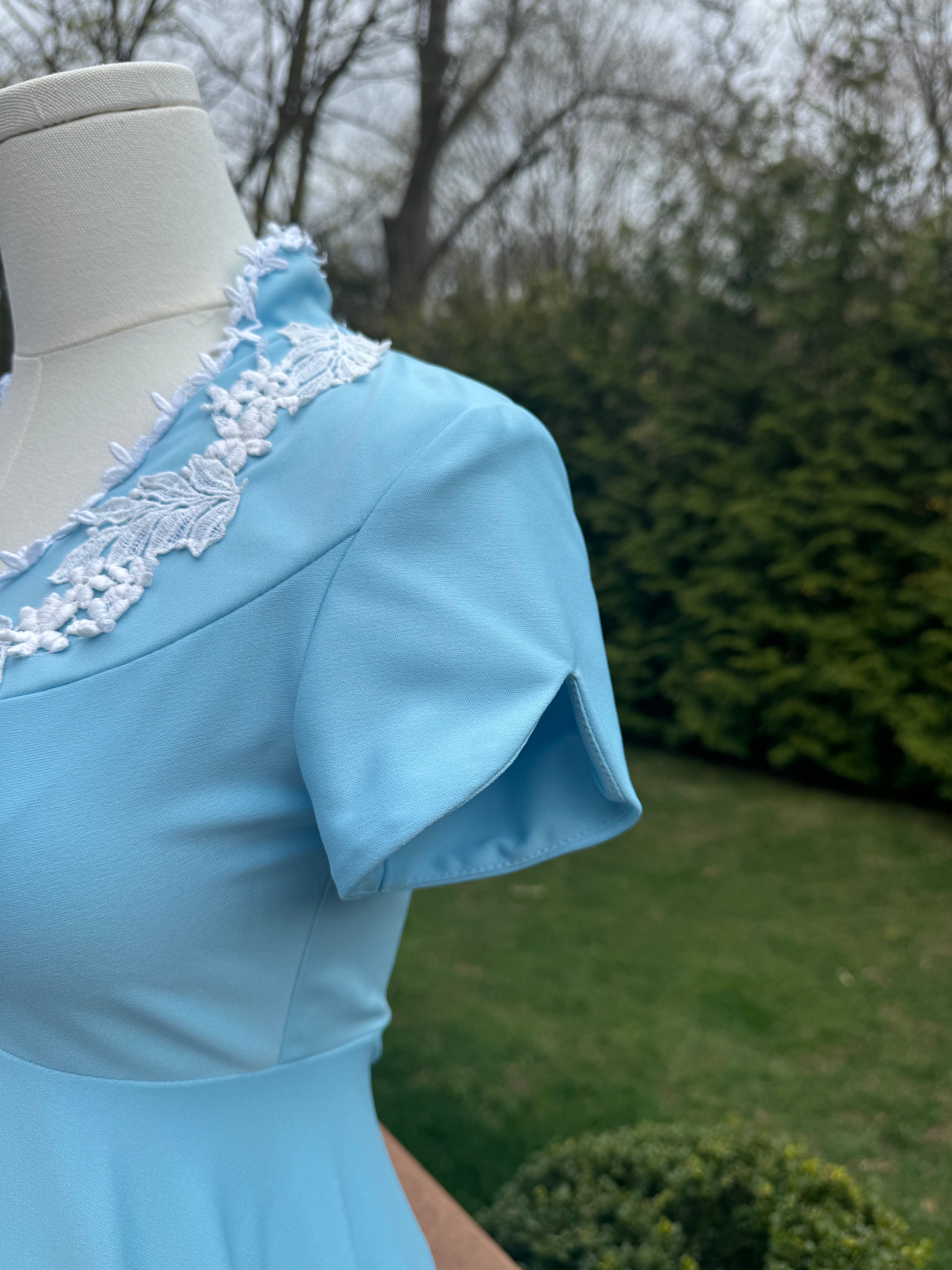 Be bold and turn heads in the jenna dress! This vintage empire waist gown features a bright blue color with playful white appliqué details. Homemade with a gorgeous 1970s silhouette, it is perfect for standing out at any summer event! Close up view of the slightly scalloped sleeves.