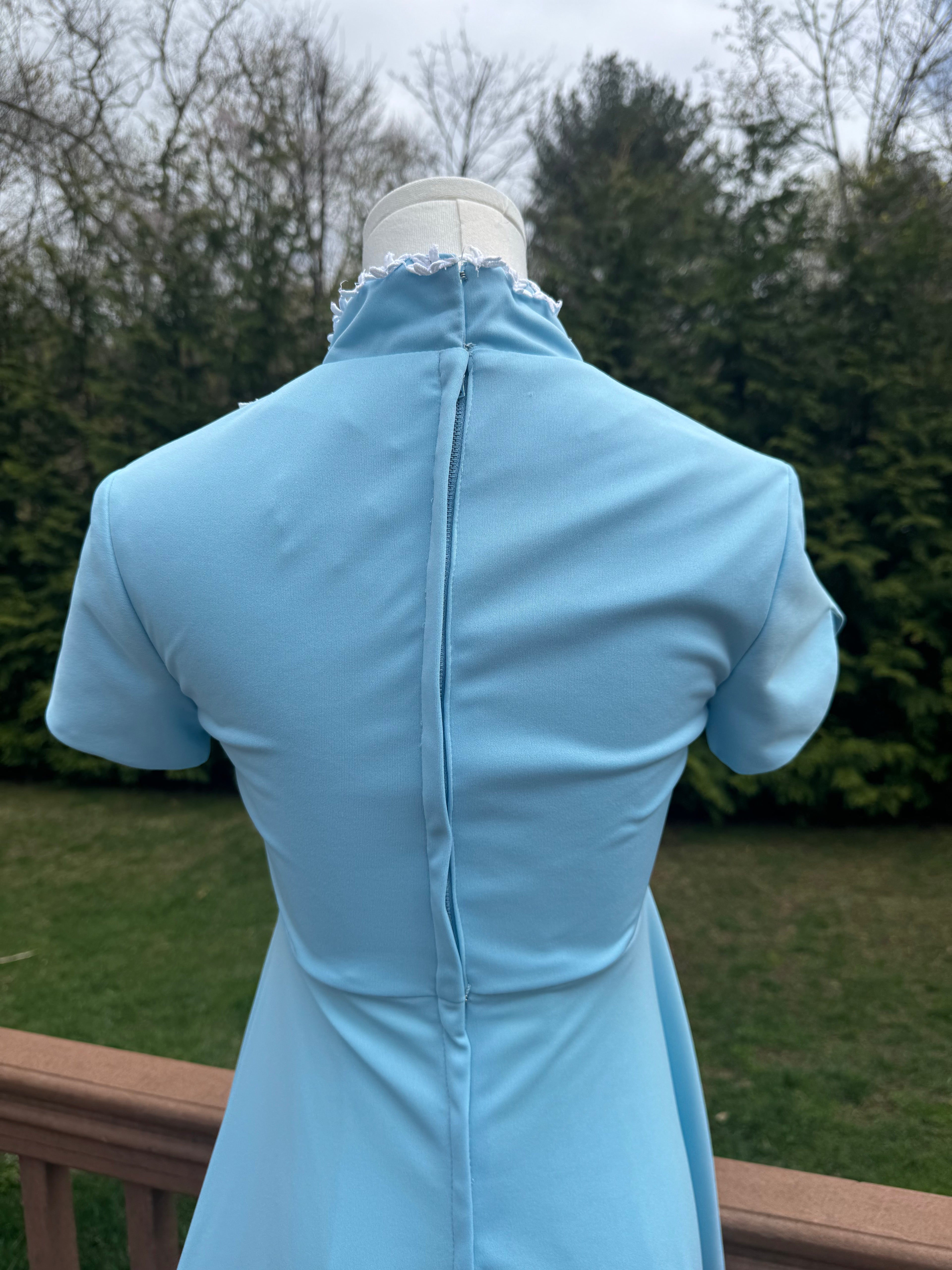 Back view of the jenna dress! This vintage empire waist gown features a bright blue color with playful white appliqué details. Homemade with a gorgeous 1970s silhouette, it is perfect for standing out at any summer event!